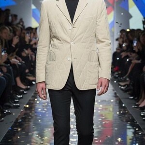May include: A beige quilted blazer with a diamond pattern, worn with black trousers and a black crew neck top. The blazer features two front pockets and three buttons. The model is on a runway.