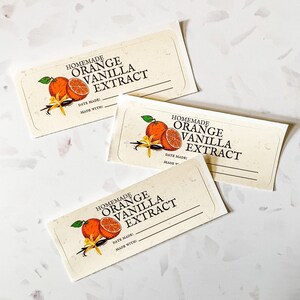 May include: Three white labels with a handwritten font that reads "Homemade Orange Vanilla Extract". Each label features a graphic of an orange slice and vanilla bean.