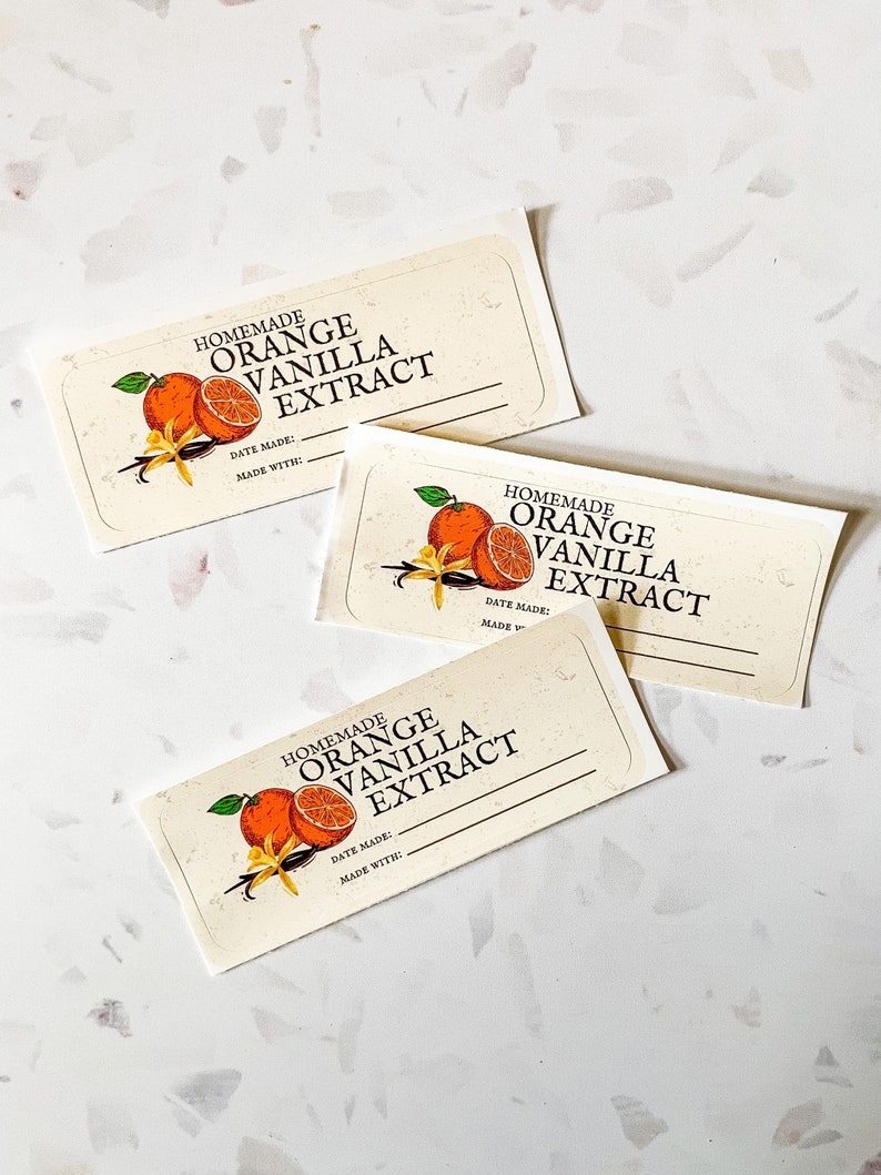 May include: Three white labels with a handwritten font that reads "Homemade Orange Vanilla Extract". Each label features a graphic of an orange slice and vanilla bean.