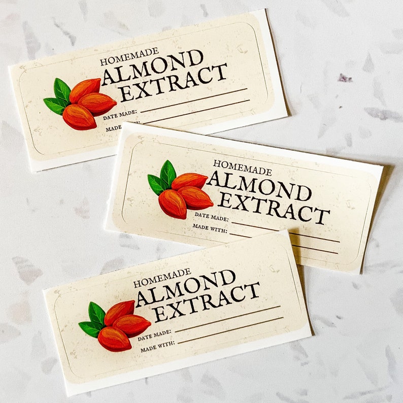 May include: Three blank labels with a cream background and brown text that reads "Homemade Almond Extract". Each label features a drawing of three almonds with green leaves.