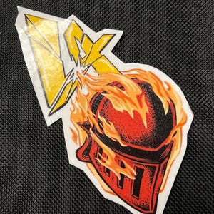May include: A red and black knight helmet engulfed in flames with a yellow lightning bolt striking it.