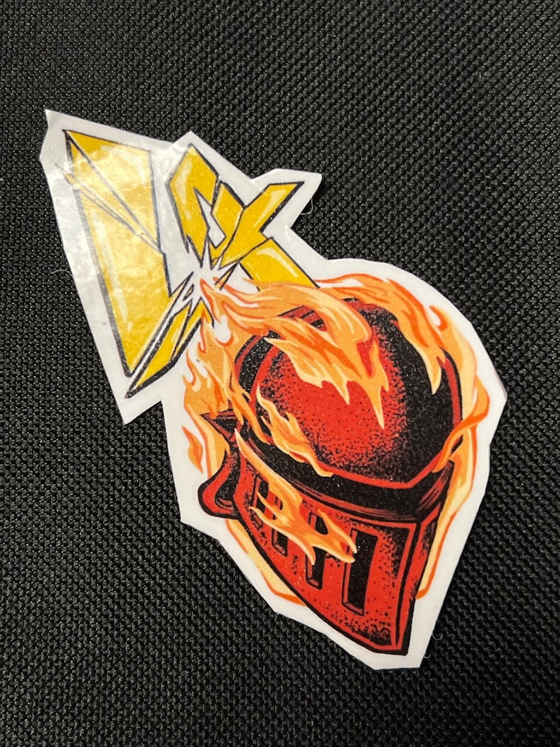 May include: A red and black knight helmet engulfed in flames with a yellow lightning bolt striking it.