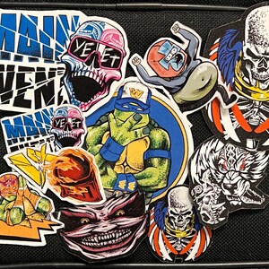 May include: A collection of colorful stickers featuring various characters and designs, including a skull with sunglasses, a Teenage Mutant Ninja Turtle, a skull with wings, and a monster with sharp teeth. The stickers are on a black background and have a variety of colors, including red, blue, green, yellow, and black.