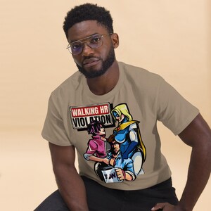 May include: A tan t-shirt featuring a graphic of three anime-style characters and the text "WALKING HR VIOLATION" in a red and white sign. The characters are in blue, pink, and purple. The person in the image is wearing glasses.