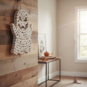 Puede incluir: Una decoraci&oacute;n de pared con forma de fantasma, construida con numerosos corchos de vino cil&iacute;ndricos de color marr&oacute;n claro dispuestos en un patr&oacute;n denso. La figura del fantasma presenta dos ojos circulares oscuros y una boca peque&ntilde;a, colgada de una cuerda de yute.