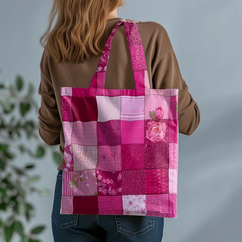 Pode incluir: Uma sacola tote rosa patchwork com uma variedade de padr&otilde;es florais e geom&eacute;tricos. A sacola &eacute; carregada por uma pessoa vestindo um su&eacute;ter marrom e jeans azuis. A sacola tote tem formato retangular e al&ccedil;as resistentes.