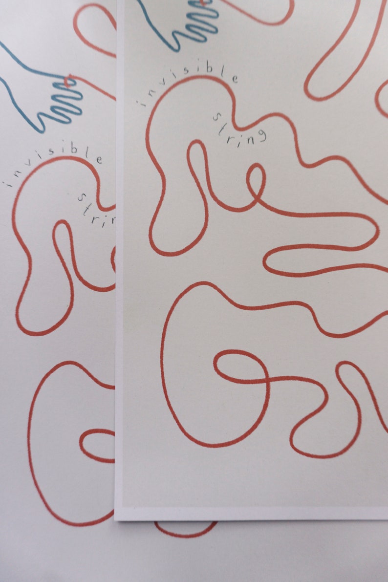 Pu&ograve; includere: Uno sfondo bianco con uno spago rosso disegnato in una linea continua che forma una serie di anelli e curve. Il testo "invisible string" &egrave; scritto in blu lungo lo spago.