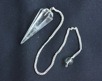 May include: A clear quartz crystal pendulum with a silver chain and a green crystal bead.