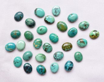 May include: A collection of 25 oval-shaped turquoise cabochons in various shades of blue and green. The stones are smooth and polished, with some showing natural veining and inclusions.