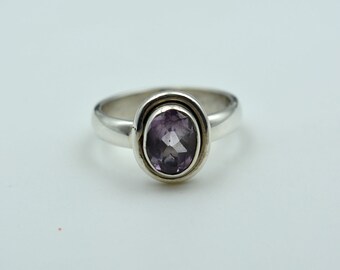 May include: A silver ring with a purple oval gemstone set in a bezel setting.