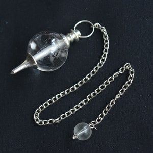 Puede incluir: Un péndulo de cristal de cuarzo transparente con una cadena de plata y un pequeño cristal de cuarzo transparente en el extremo de la cadena.