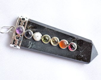 Puede incluir: Péndulo de obsidiana negra con siete piedras de chakra. Las piedras son púrpura, índigo, azul, blanco, verde, amarillo y naranja. El colgante tiene una anilla de plata.
