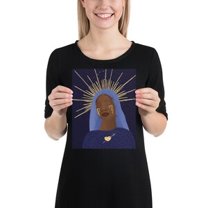 May include: A digital illustration of a woman with dark skin wearing a blue robe and a gold halo. She has gold tears streaming down her face and a gold heart with a cross on her chest. The background is a dark blue with gold stars.