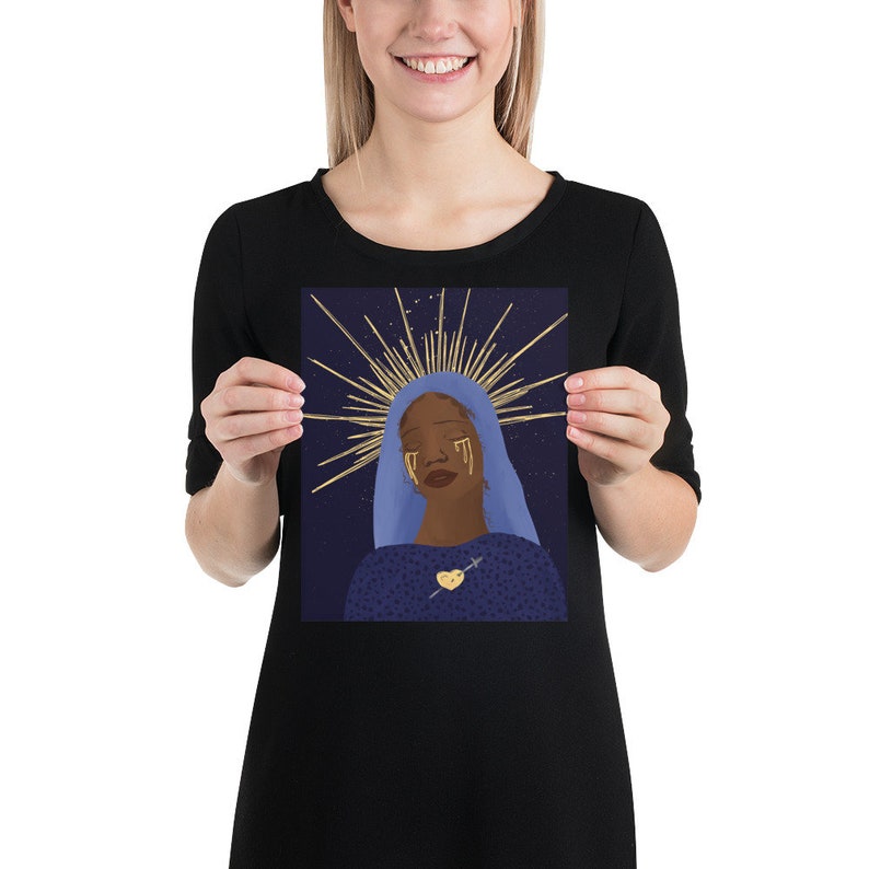 May include: A digital illustration of a woman with dark skin wearing a blue robe and a gold halo. She has gold tears streaming down her face and a gold heart with a cross on her chest. The background is a dark blue with gold stars.
