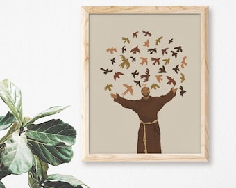 May include: A framed print of a religious illustration featuring a man in brown robes with his arms outstretched, surrounded by a flock of colourful birds. The background is a light beige colour.