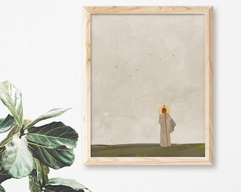 May include: A framed print of a painting depicting a person in a white robe standing in a field with a halo above their head. The background is a light gray with a few birds flying in the sky.