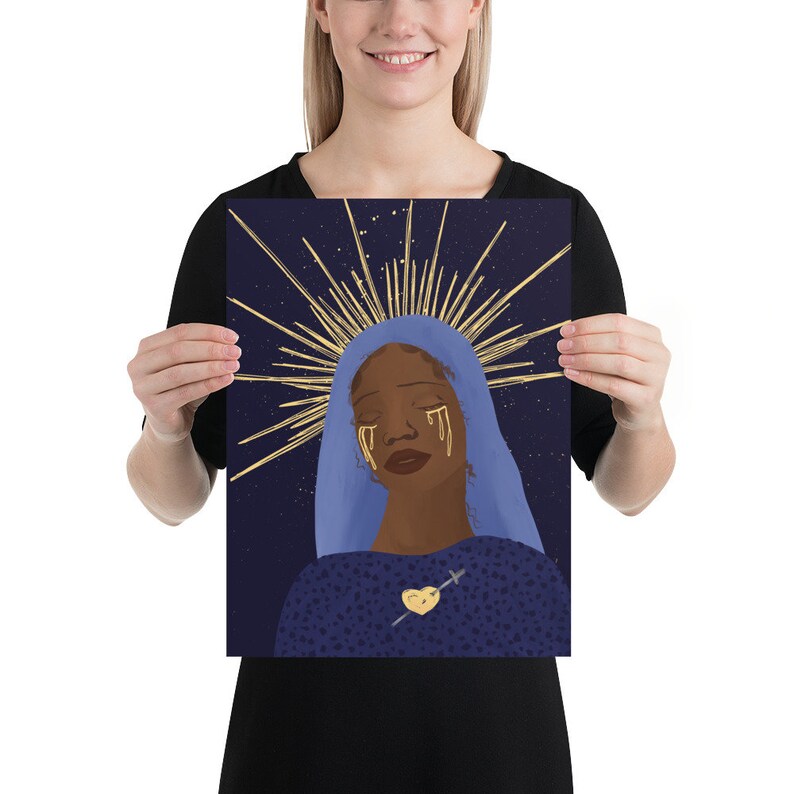 May include: A digital illustration of a woman with dark skin wearing a blue robe and a gold halo. Her eyes are closed and she has gold tears streaming down her face. She is wearing a gold heart with a cross on her chest. The background is a dark blue with gold stars.