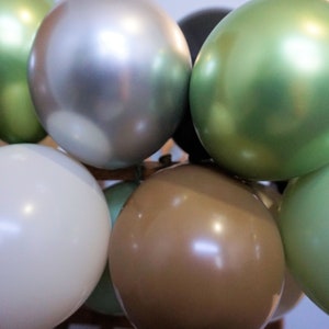 May include: A cluster of balloons in a variety of colours, including green, silver, brown, and white. The balloons are arranged with some overlapping.