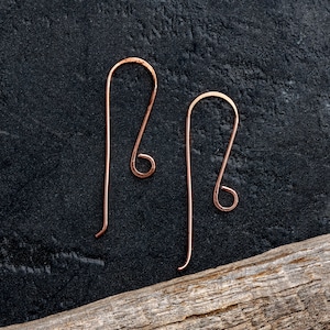 May include: Two copper wire earring hooks with a simple loop design. The hooks are on a black background.