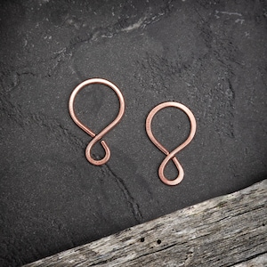 May include: Two copper infinity symbol earrings on a dark grey background. The earrings are made of a single piece of wire that is twisted into an infinity symbol.