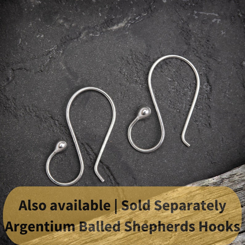 May include: Two silver ball ended shepherd's hooks, also known as French hooks, are shown on a dark gray textured surface.  Also available | Sold Separately Argentium Balled Shepherds Hooks