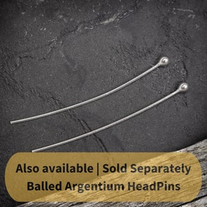 May include: Two silver ball-headed headpins on a dark gray textured surface. The text "Also available | Sold Separately Balled Argentium HeadPins" is on a gold background.