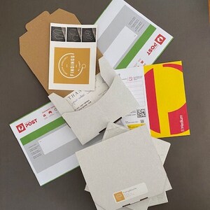 May include: A white envelope with a handwritten note inside, a brown cardboard envelope, a white envelope with a green and white label that says "Post", a yellow envelope with a red "Post" logo and the word "Medium", and a yellow card with a logo that says "FINDINGS" and the text "Thank you for your order.  We hope you enjoy your new jewelry!"