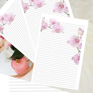 Könnte beinhalten: Drei Blätter liniertes Papier mit einem rosa Orchideenrand. Das Papier ist weiß mit dünnen grauen Linien.