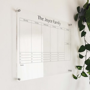Könnte beinhalten: Ein transparenter, wöchentlicher Planer aus Acryl mit dem Text "The Joyce Family" oben. Der Planer hat Spalten für jeden Tag der Woche, von Montag bis Sonntag, mit Platz für Notizen unten.