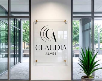 May include: A clear acrylic sign displaying the name "CLAUDIA ALVES" in black. The sign is fixed to a white wall with gold fixings. The sign features a "CA" logo. The words "Acrylic Sign Art" are in the bottom right corner.