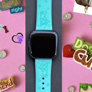 May include: A turquoise blue silicone watch band with a small Yorkshire Terrier dog engraved on it. The band has a black watch face and is surrounded by various dog-themed decorations, including paw prints, hearts, and a sign that says "Dog Gone Cute".