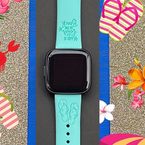 May include: A turquoise blue Apple Watch band with a white design of flip flops and the text "Life is better at the beach".