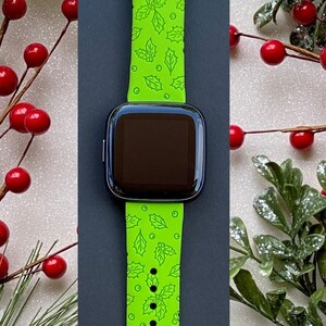 Puede incluir: Una pulsera de reloj inteligente de color verde brillante con un patr&oacute;n de hojas de acebo y bayas. La pulsera est&aacute; hecha de silicona y es compatible con la mayor&iacute;a de los relojes inteligentes.