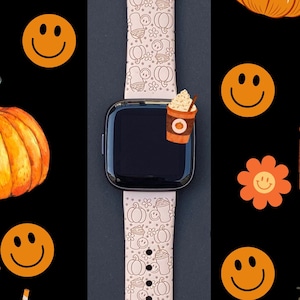 May include: A pink Apple Watch band with a fall-themed design featuring pumpkins, coffee cups, and smiley faces. The band is made of silicone and has a white background with brown and orange accents.