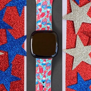 May include: A smartwatch band with a red, white, and blue popsicle print. The band is made of silicone and is compatible with most smartwatches.