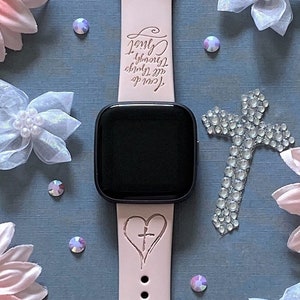 K&ouml;nnte beinhalten: Ein rosafarbenes Silikon-Armband mit einem schwarzen Zifferblatt. Das Armband hat ein Kreuz- und Herzdesign mit dem Text "Love beyond measure, cherish the moments, you're my always".