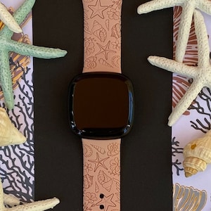 Op de afbeelding: Een roze siliconen horlogeband met een schelp- en zeester-ontwerp. De band is compatibel met smartwatches.