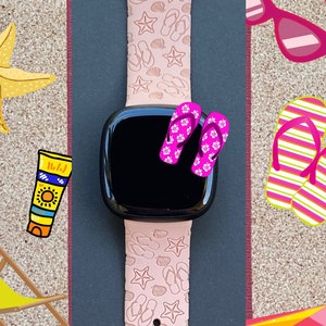 May include: A pink watch band with a white and pink seashell and flip-flop pattern. The watch band is on a dark gray background with beach-themed illustrations.