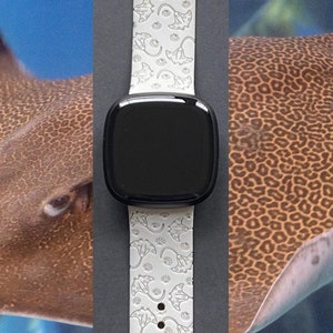 May include: White silicone Apple Watch band with a pattern of stingrays. The band is shown on a gray background.