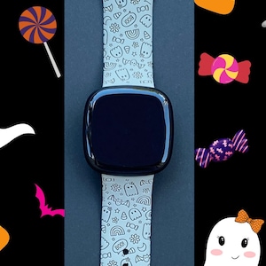 May include: A light gray silicone watch band with a black watch face. The band is decorated with a white and black pattern of ghosts, candy corn, bats, and other Halloween-themed imagery.