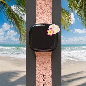 May include: A pink silicone watch band with a seashell and starfish pattern. The band is shown on a black background with a smartwatch face.