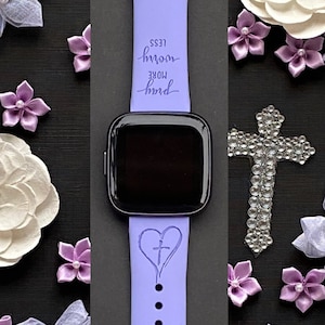 May include: A purple silicone watch band with a heart and cross design. The band has the text "more hard less room" engraved on it.
