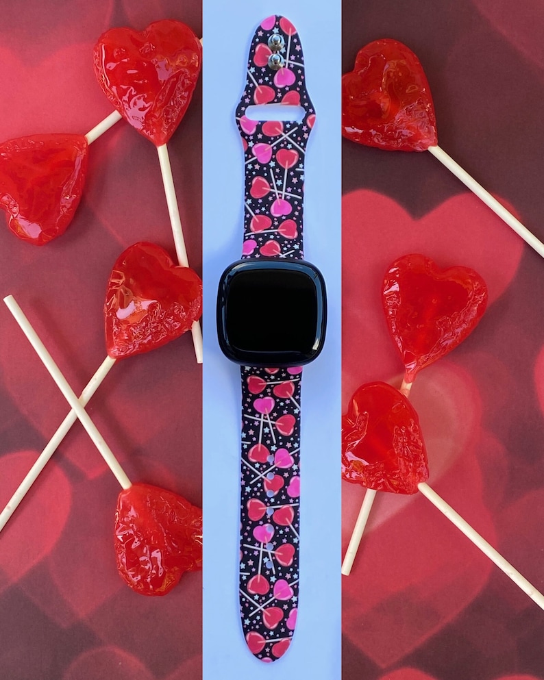 K&ouml;nnte beinhalten: Eine schwarze Smartwatch mit einem pink-schwarzen Armband mit Herz- und Lollipop-Muster. Das Armband ist aus Silikon und hat eine glatte Oberfl&auml;che.
