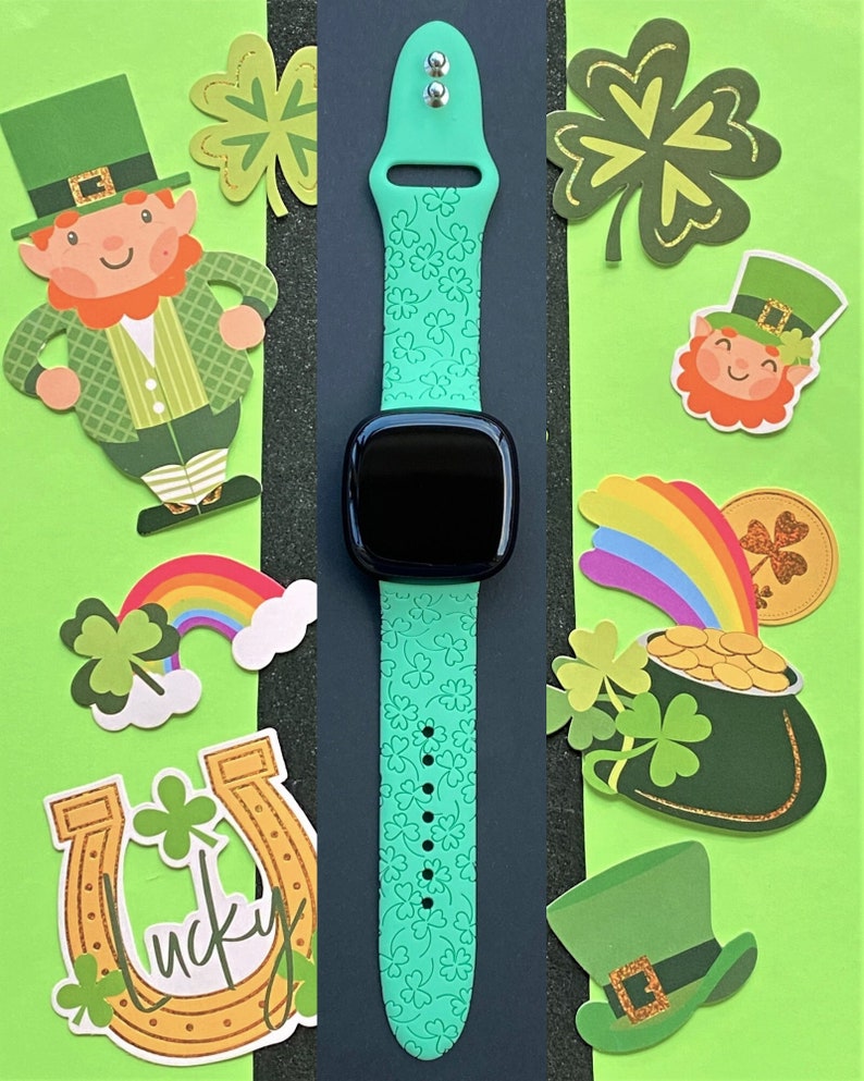 May include: A green smartwatch band with a shamrock pattern. The band is on a black background with a variety of St. Patrick's Day themed cutouts.