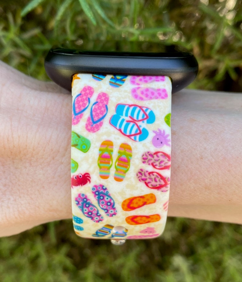 May include: A white watch band with a colorful print of flip flops. The band is made of silicone and has a black watch face.