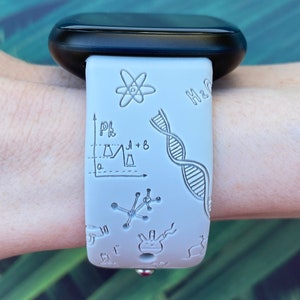 Pu&ograve; includere: Cinturino per orologio in silicone bianco a tema scientifico. Il cinturino presenta una variet&agrave; di illustrazioni scientifiche, tra cui una catena di DNA, un atomo, una beuta e un grafico. Il testo "H2O" &egrave; anche visibile sul cinturino.