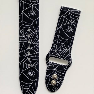 May include: Black and white watch band with a spider web and spider design.