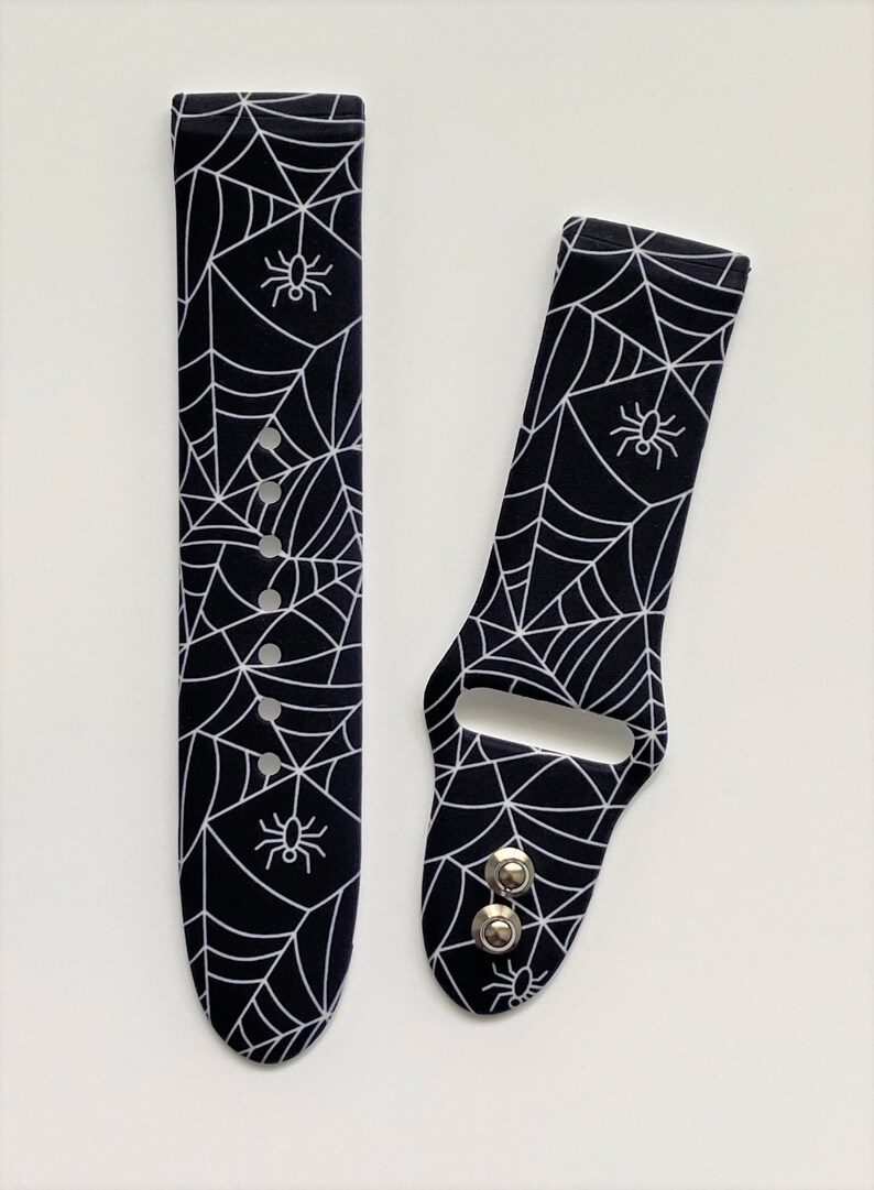 May include: Black and white watch band with a spider web and spider design.