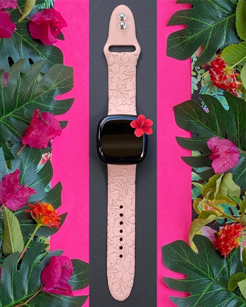 Puede incluir: Una correa de reloj de silicona rosa con un patr&oacute;n floral. La correa est&aacute; dise&ntilde;ada para un reloj inteligente y tiene una esfera negra.