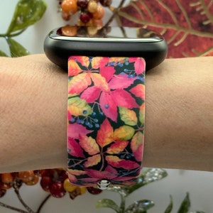 May include: A pink and orange watch band with a fall leaf pattern. The band is made of silicone and has a black watch face.